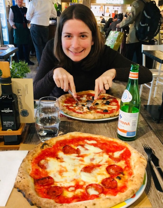 woman smiling and eating a pizza in a restaurant