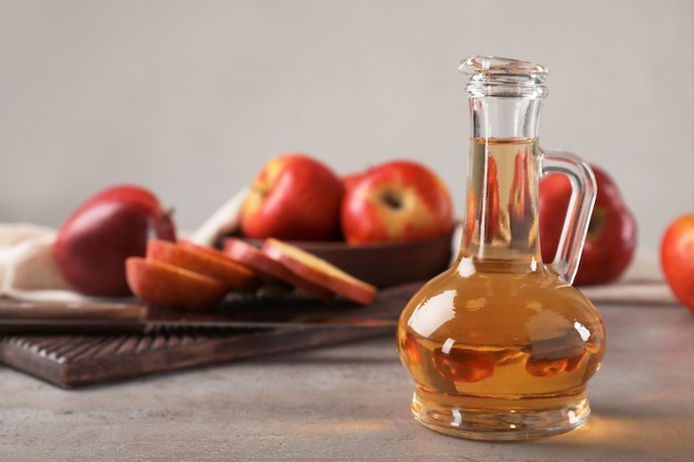 Composition with jug of apple vinegar on table