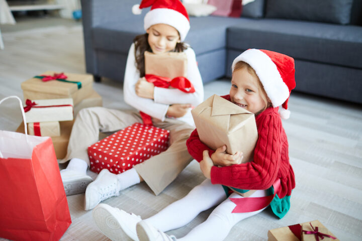 twee jonge meisjes openen cadeautjes op Eerste Kerstdag
