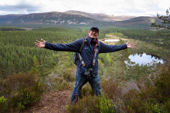 Man enjoying being in the wild, with forest and mountains in the background