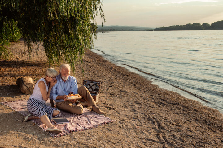 Shot of a happy senior couple having a picnic at the riverbank