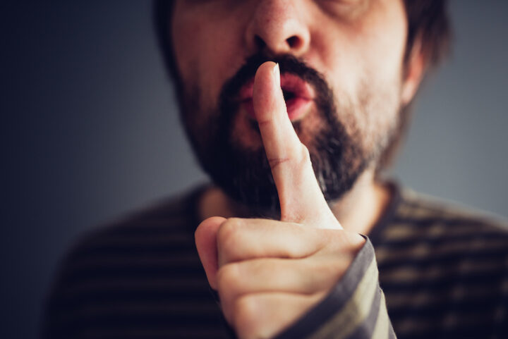 Man saying hush or be quiet with finger on lips