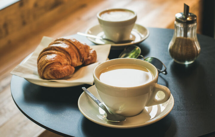 Coffee latte, cappuccino and croissant on small table in cafe, French or Italian breakfast concept, square crop