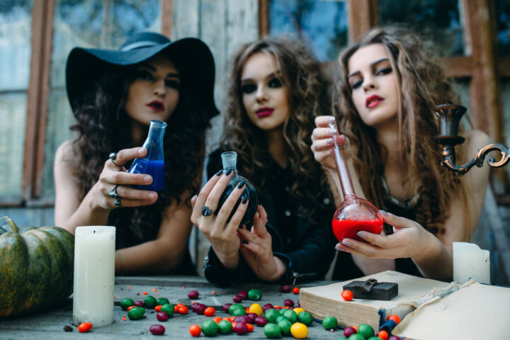 three women dressed as witches with magic potions in their hands