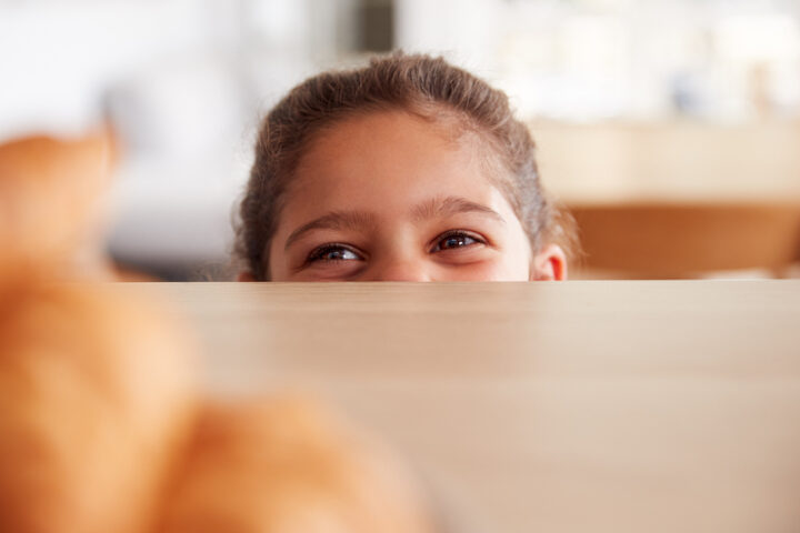 smiling girl hiding behind the table