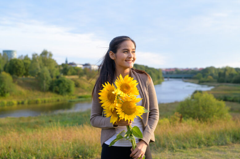 Portrait Of Young Beautiful Asian Woman Against Relaxing View Of The River And Lush Green Field