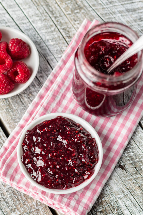 Raspberries and raspberry jam on white wooden table