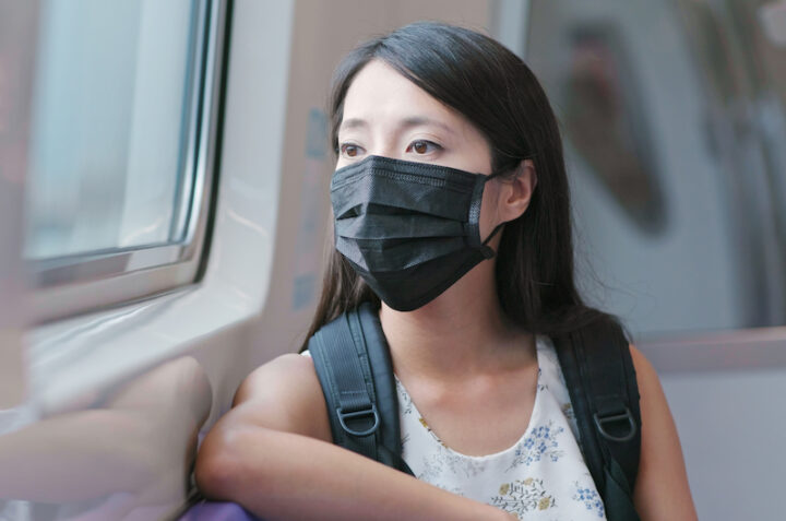 Woman wearing protective mask and taking train