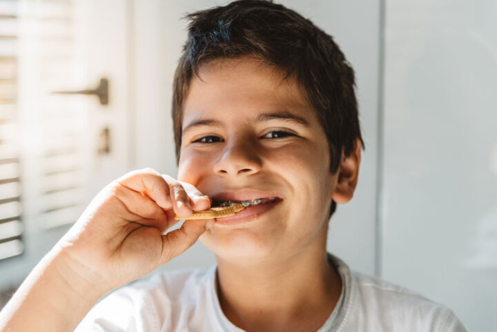 Smiling young boy with braces eating biscuit