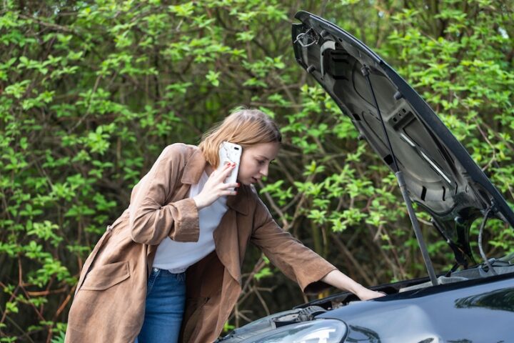 Girl checking the engine of her car.