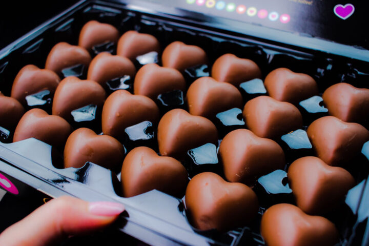 nő kezében egy doboz szív alakú csokoládé
