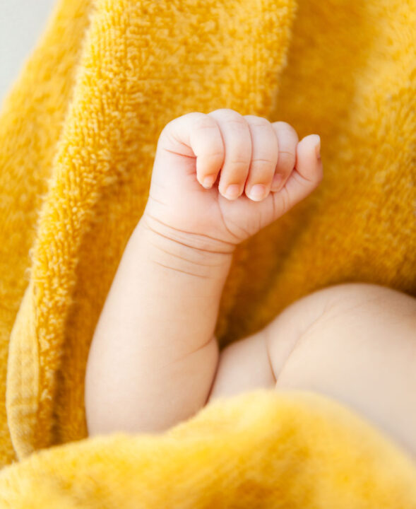 Newborn fist with yellow blanket around