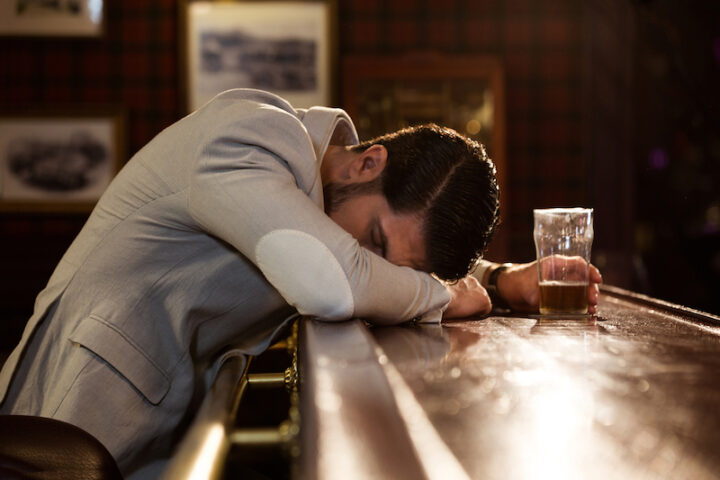 Young drunk man sleeping on a pub counter