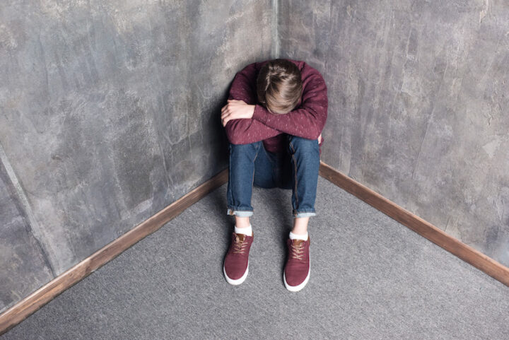 High angle view of depressed teenager sitting on the floor