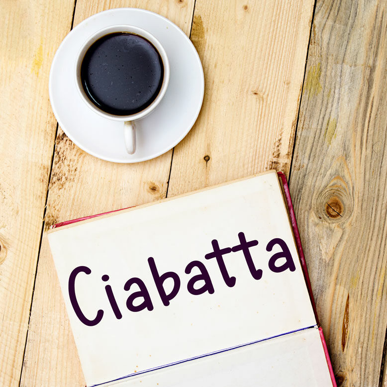 cover image with the word “ciabatta” and its translation written on a notepad next to a cup of cofee
