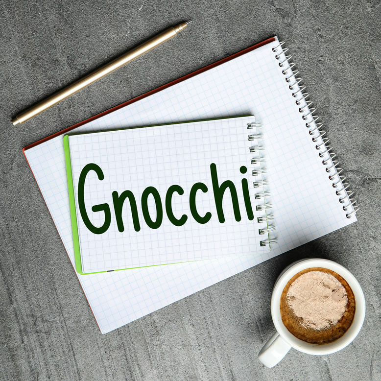 cover image with the word “gnocchi” written on a notepad next to a cup of cofee