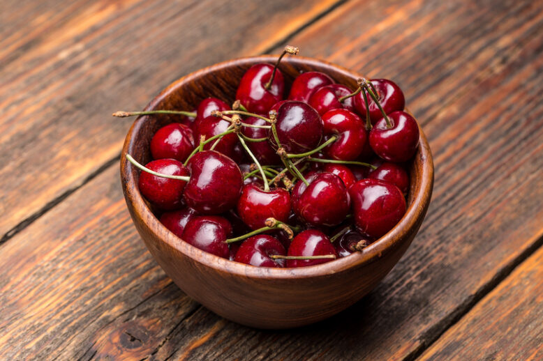 Wooden bowl full of cherries on the table