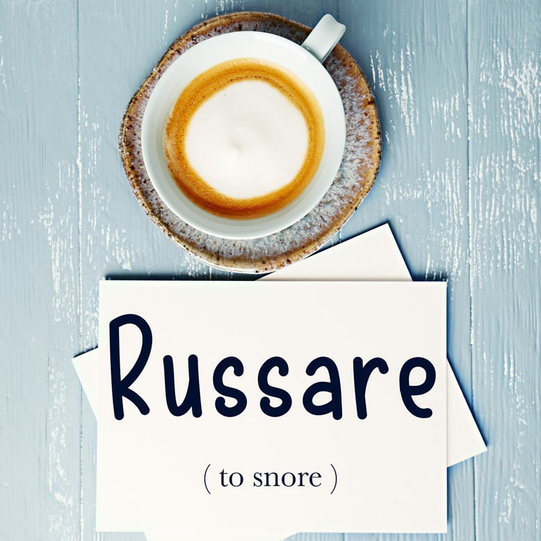 cover image with the word “russare” and its translation written on a notepad next to a cup of cofee