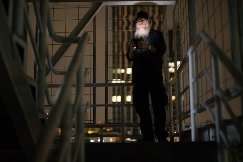 Portrait of mature bearded man looking suspicious at dark staircase