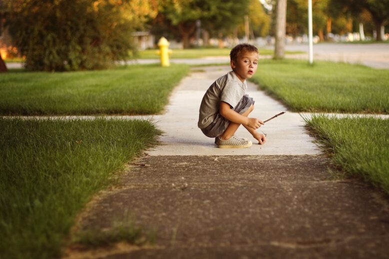 A boy playing on the sidewalk