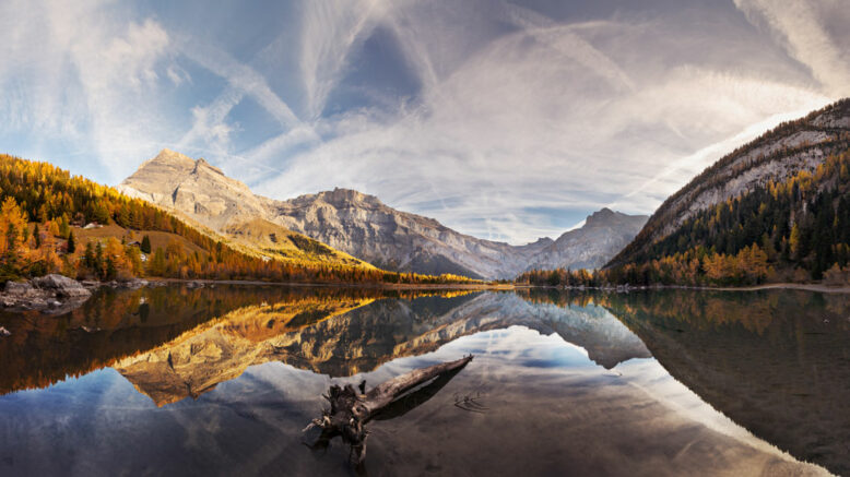 Spectacular scenery of lake with smooth surface reflecting amazing mountain range and sky