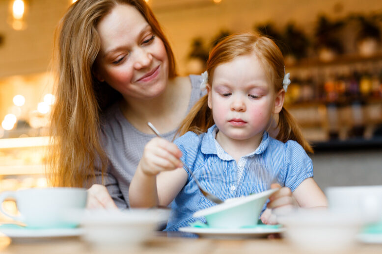 Young woman and her daughter having tasty dessert