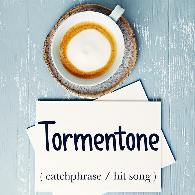 cover image with the word “tormentone” and its translation written on a notepad next to a cup of coffee