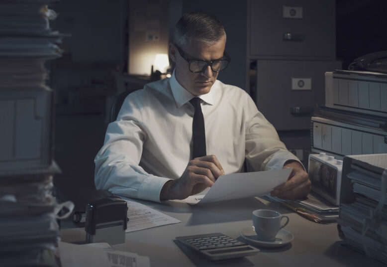 Businessman working overtime, he is overloaded with paperwork