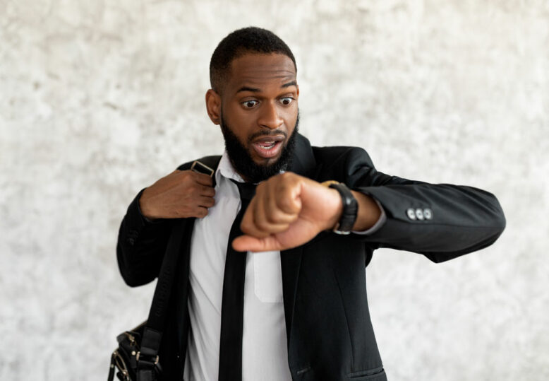 Portrait of shocked worried black business man with open mouth looking at wrist watch