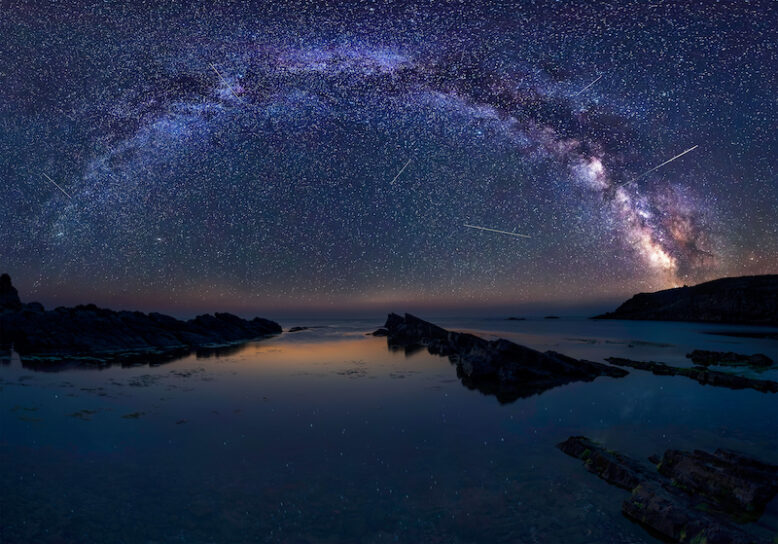Night sky with milky way over water and rocks