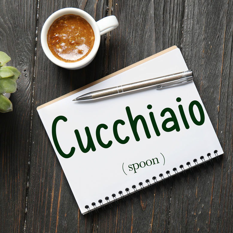 cover image with the word “cucchiaio” and its translation written on a notepad next to a cup of coffee