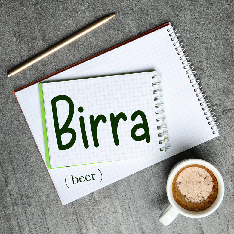 cover image with the word “birra” and its translation written on a notepad next to a cup of coffee
