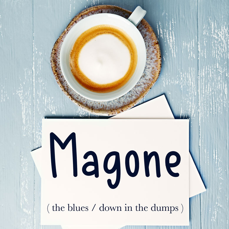 cover image with the word “magone” and its translation written on a notepad next to a cup of coffee