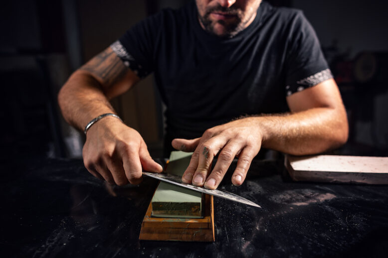 man using whetstone to sharpening chef knife
