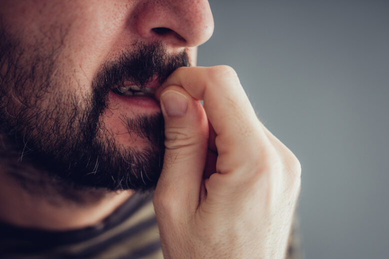 Close up of nervous male biting fingernails