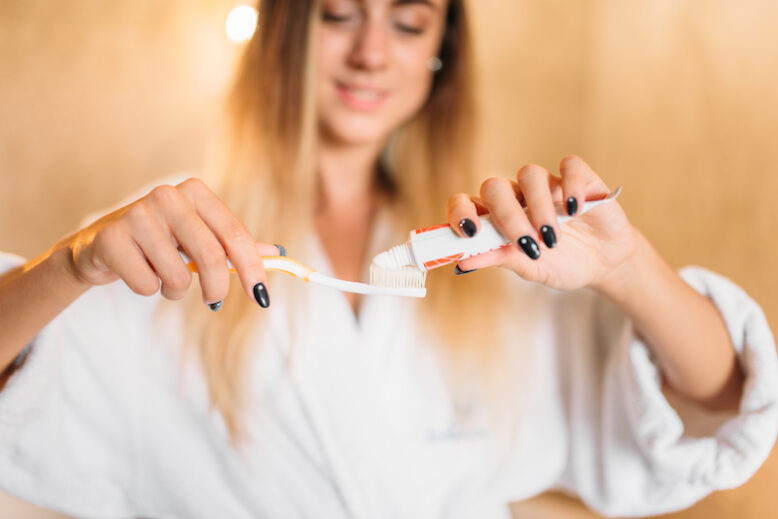 Young woman with toothbrush and toothpaste in hand.