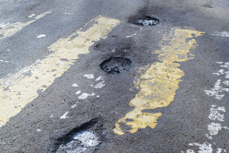 Pits on the road, destroyed asphalt, erased markings of a pedestrian crossing