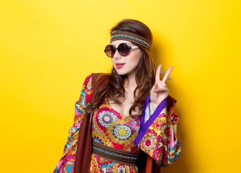 Young hippie girl with sunglasses on yellow background
