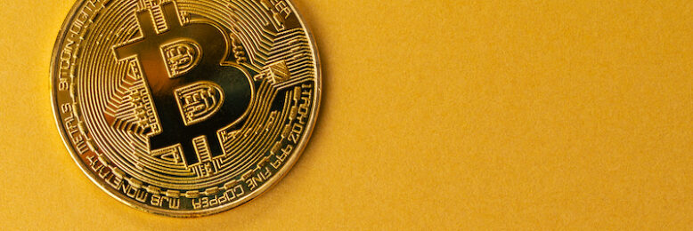 Close-up of a gold bitcoin coin. Virtual money or blockchain cryptocurrency. Large copyspace gold yellow backgound .
