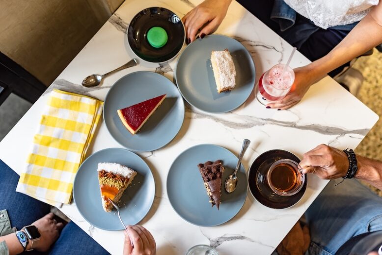 Close-up on a table with people eating cakes.