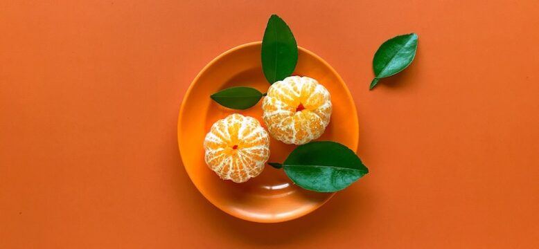 two peeled mandarin oranges on an orange plate