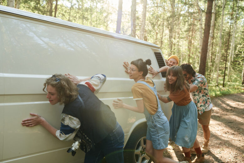 Group of people pushing the van together during journey on the nature