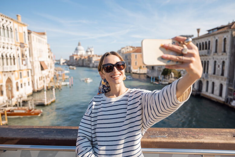 Young woman taking selfie photo on the background of famous Grand Canal in Venice. 