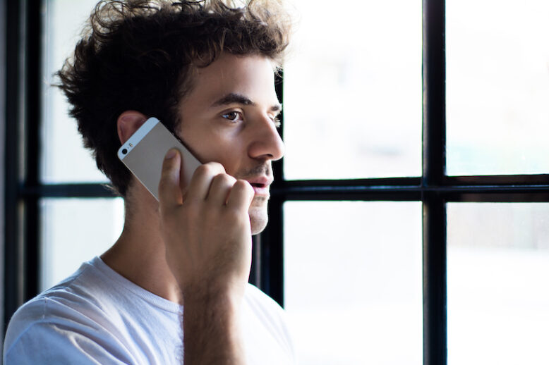 portrait of young man talking on the phone at home.