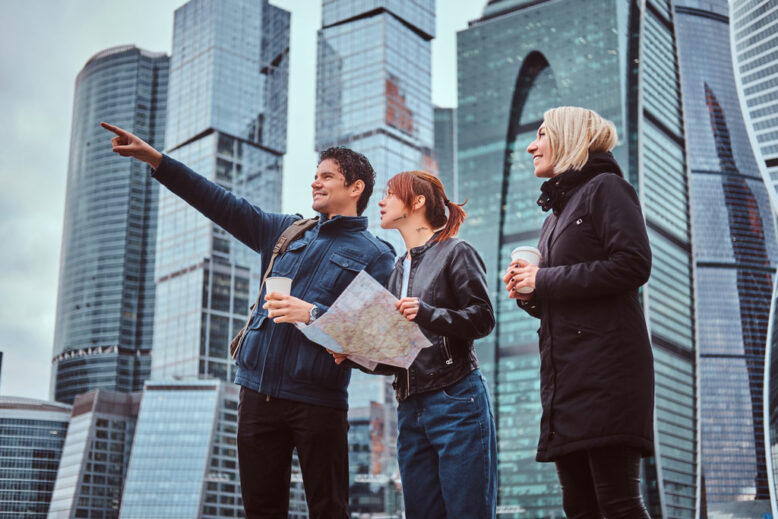 Man showing the right direction to female tourists in front of skyscrapers