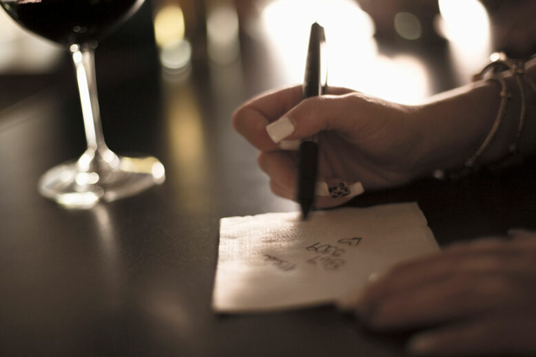 Close up of woman writing phone number on a napkin in bar