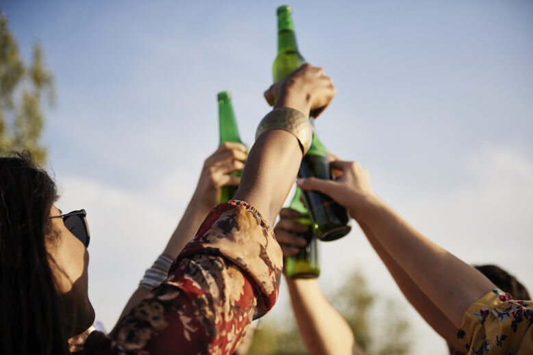 Group of people doing celebratory toast with beer bottles