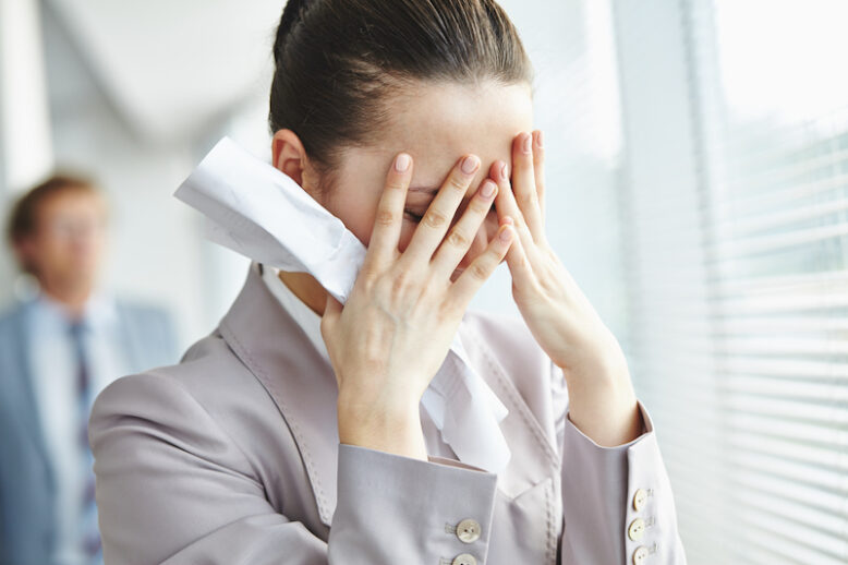 Unhappy businesswoman hiding her face in hands