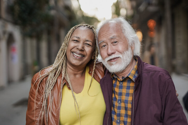 Happy multiracial elderly couple smiling at camera outdoors