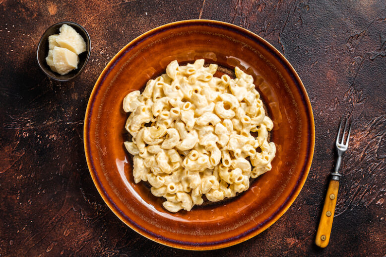 Macaroni Mac and cheese with Cheddar sauce in a plate. Dark background. Top view.